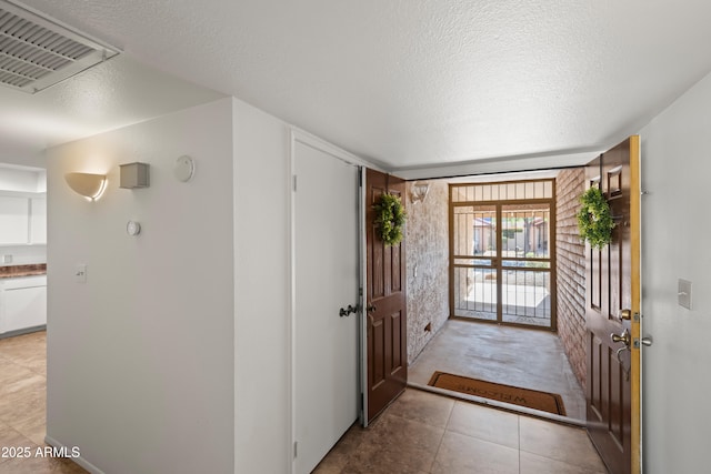 entryway with light tile patterned flooring, visible vents, and a textured ceiling