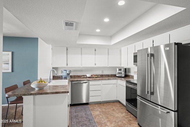 kitchen with a sink, a peninsula, dark countertops, and stainless steel appliances