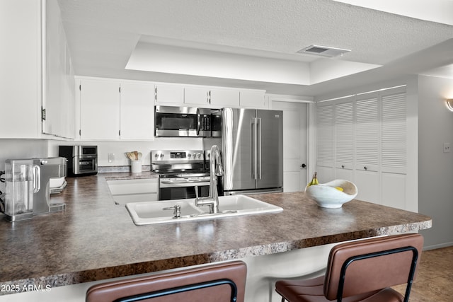 kitchen with stainless steel appliances, dark countertops, visible vents, and a peninsula