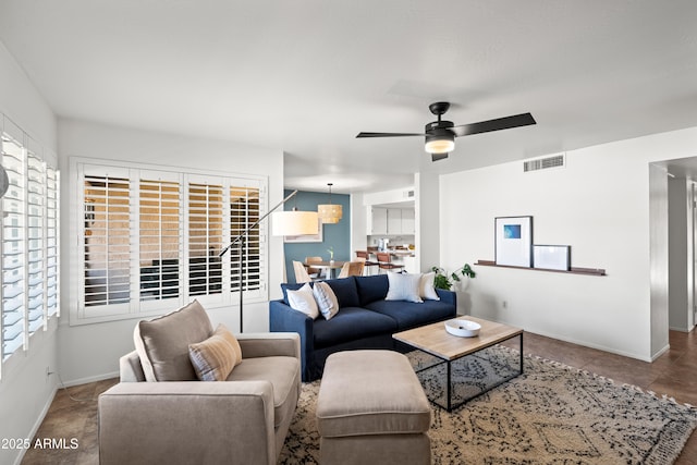 living room featuring visible vents, a healthy amount of sunlight, baseboards, and a ceiling fan