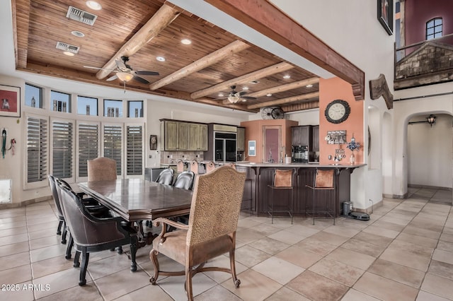 dining room featuring beam ceiling, wood ceiling, light tile patterned floors, and a towering ceiling