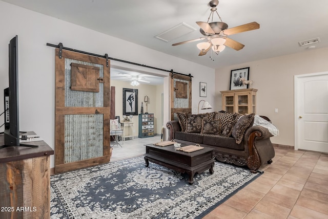 living room with a barn door, ceiling fan, and light tile patterned floors