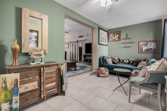 living room featuring a barn door, ceiling fan, and light tile patterned flooring