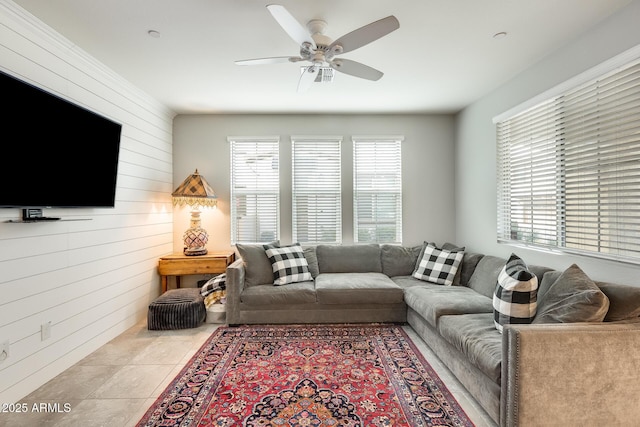 living room with ceiling fan, light tile patterned floors, and wood walls