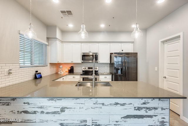 kitchen featuring hanging light fixtures, appliances with stainless steel finishes, and white cabinets