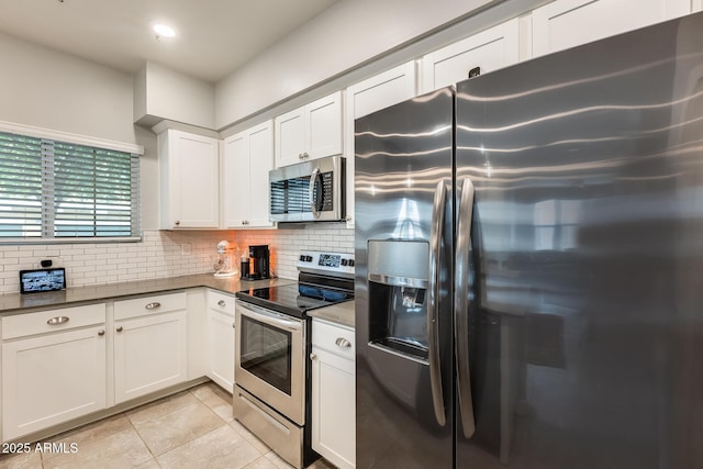 kitchen with white cabinetry, appliances with stainless steel finishes, light tile patterned flooring, and decorative backsplash