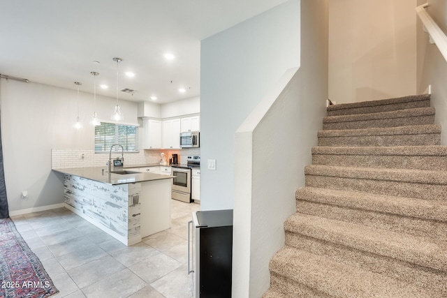 kitchen featuring pendant lighting, sink, white cabinets, kitchen peninsula, and stainless steel appliances