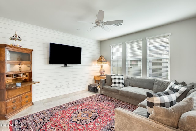 tiled living room with ceiling fan and wood walls