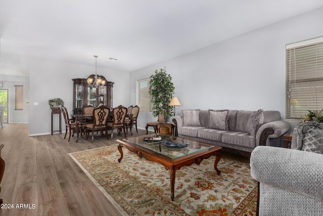 living area featuring visible vents, a notable chandelier, baseboards, and wood finished floors