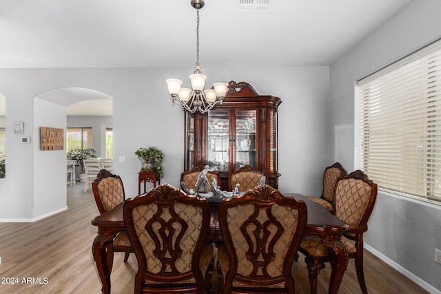 dining area featuring arched walkways, a notable chandelier, baseboards, and wood finished floors