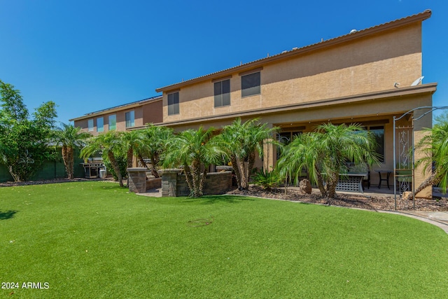 rear view of house with a lawn and stucco siding