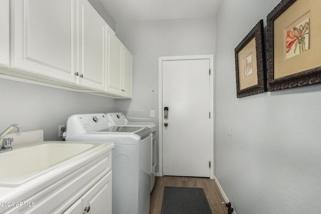 laundry room featuring cabinet space, baseboards, washer and clothes dryer, light wood-style flooring, and a sink