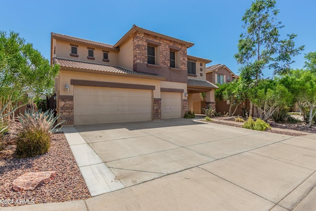 mediterranean / spanish-style home with stone siding, an attached garage, and driveway