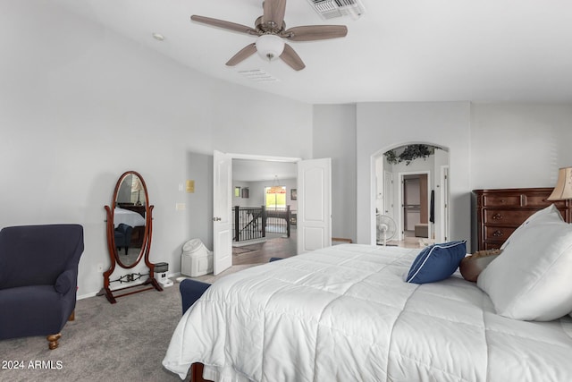 bedroom with light carpet, arched walkways, visible vents, and baseboards