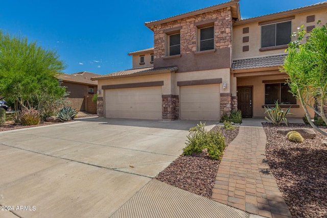 view of front of home with a garage, stone siding, driveway, and stucco siding