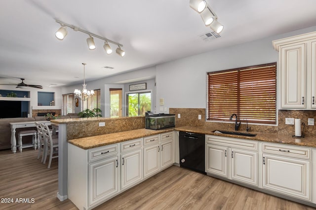 kitchen featuring a peninsula, a sink, visible vents, black dishwasher, and hanging light fixtures