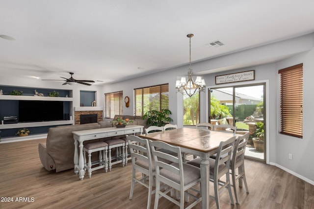 dining area with ceiling fan with notable chandelier, a wealth of natural light, visible vents, and wood finished floors