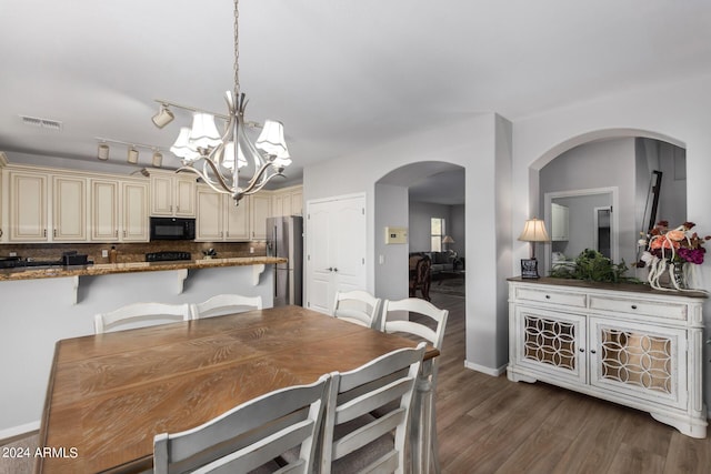 dining space with baseboards, visible vents, dark wood finished floors, arched walkways, and an inviting chandelier