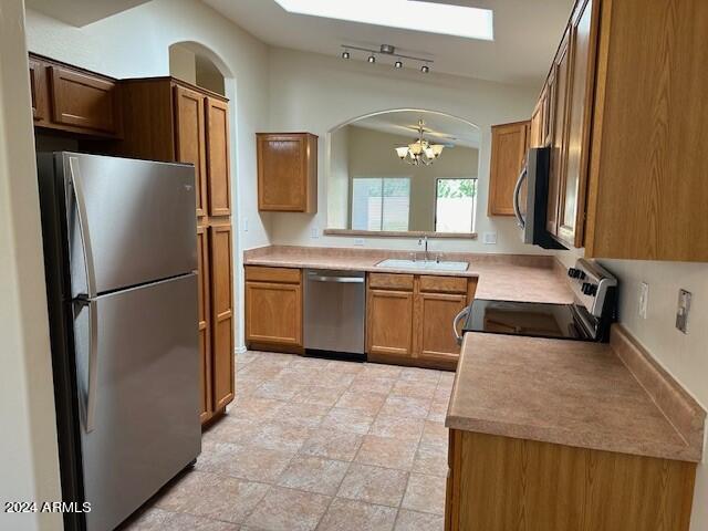 kitchen with stainless steel appliances, lofted ceiling, a chandelier, and sink