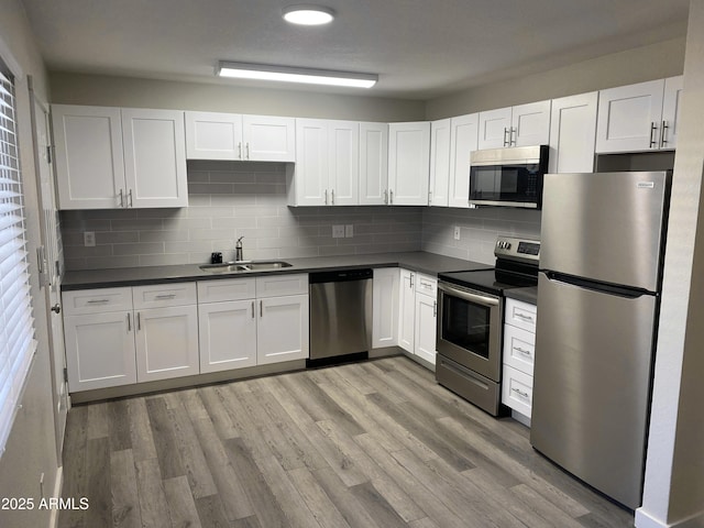 2709 E Willetta St, Phoenix, AZ 85008 - kitchen with white cabinetry, dark countertops, stainless steel appliances, light wood finished floors, and a sink