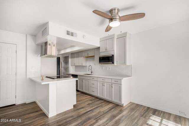 kitchen featuring sink, kitchen peninsula, ceiling fan, gray cabinets, and dark wood-type flooring