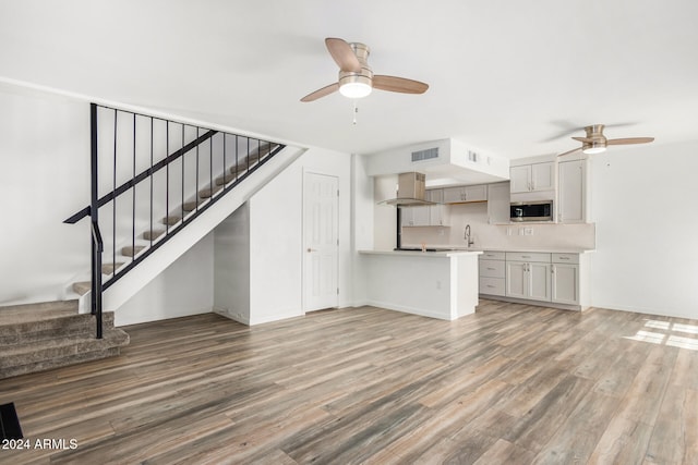 unfurnished living room featuring ceiling fan, hardwood / wood-style flooring, and sink