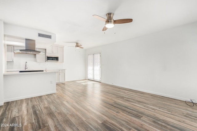 unfurnished living room featuring ceiling fan and hardwood / wood-style flooring