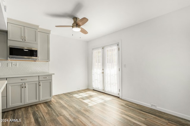 kitchen featuring hardwood / wood-style floors, ceiling fan, backsplash, gray cabinets, and french doors