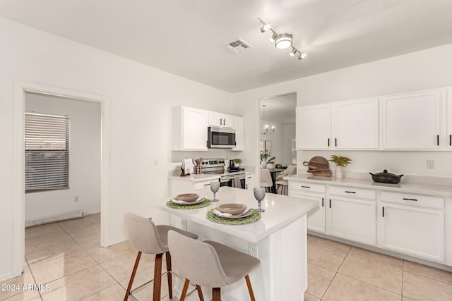 kitchen with a breakfast bar, light tile patterned floors, white cabinetry, and appliances with stainless steel finishes