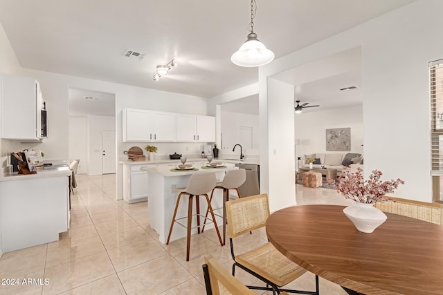 kitchen with ceiling fan, sink, hanging light fixtures, a kitchen bar, and white cabinets