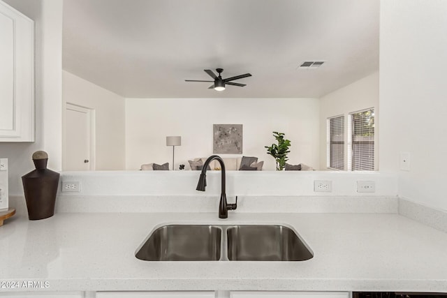 kitchen featuring light stone countertops, sink, and ceiling fan