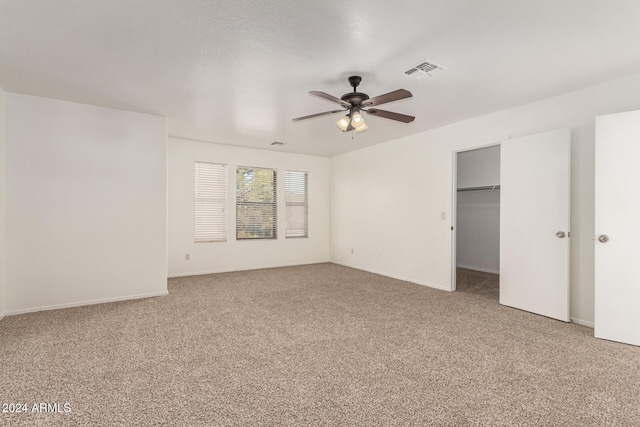 unfurnished bedroom featuring a spacious closet, ceiling fan, carpet floors, and a closet