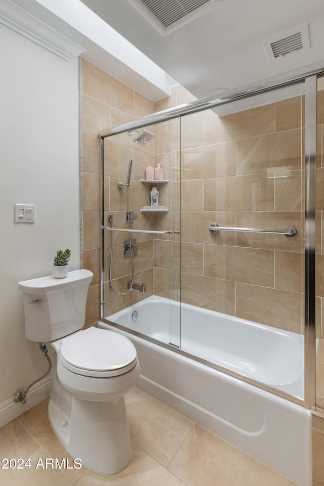 bathroom with tile patterned flooring, combined bath / shower with glass door, and toilet