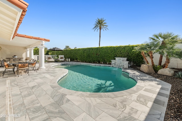 view of swimming pool with pool water feature and a patio area