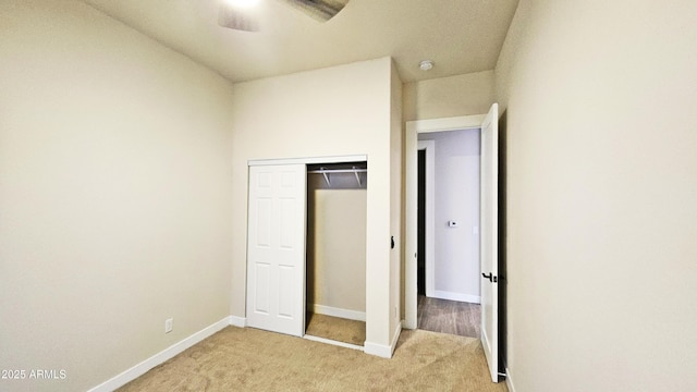 unfurnished bedroom featuring ceiling fan, a closet, and light carpet