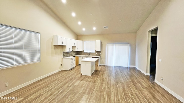 kitchen with light hardwood / wood-style flooring, sink, a kitchen island, and white cabinets