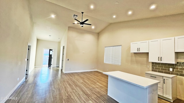 kitchen with tasteful backsplash, light hardwood / wood-style floors, a center island, and white cabinets