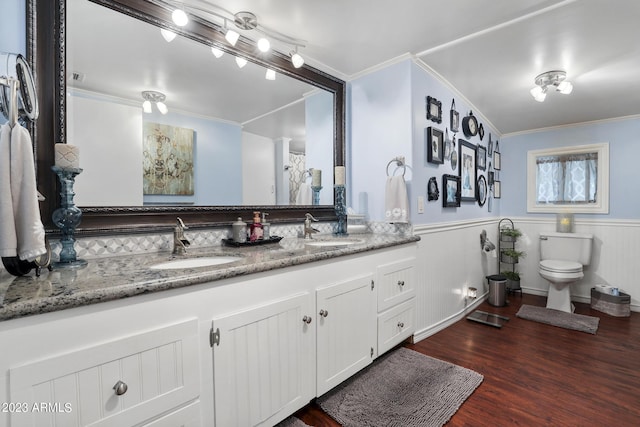 bathroom featuring wainscoting, crown molding, and a sink