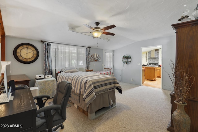 bedroom with lofted ceiling, light colored carpet, ceiling fan, and ensuite bathroom