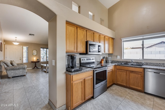 kitchen featuring sink, high vaulted ceiling, stainless steel appliances, and decorative light fixtures