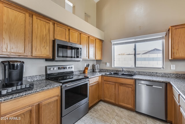 kitchen with stainless steel appliances, dark stone countertops, and sink