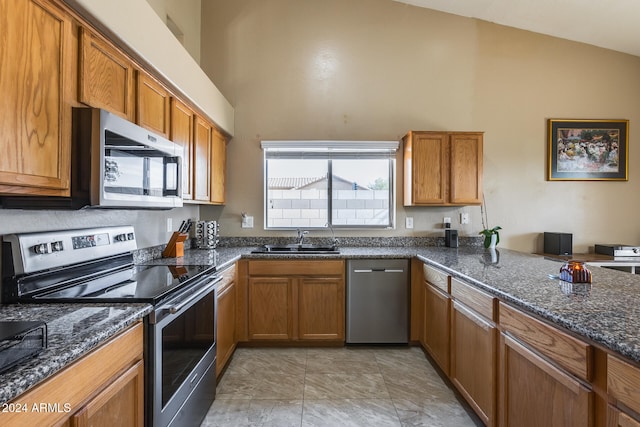 kitchen featuring dark stone countertops, lofted ceiling, sink, and appliances with stainless steel finishes