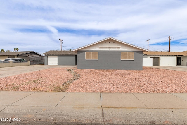 ranch-style home with a garage, concrete driveway, an outbuilding, and fence