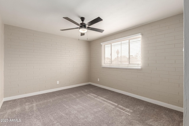 spare room featuring carpet flooring, ceiling fan, and brick wall