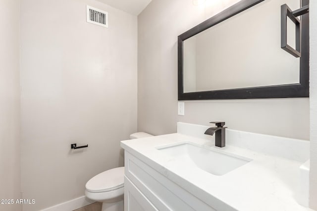 bathroom featuring toilet, vanity, visible vents, and baseboards