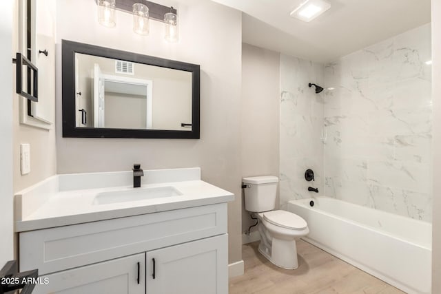 full bath with visible vents, toilet, wood finished floors, vanity, and shower / washtub combination