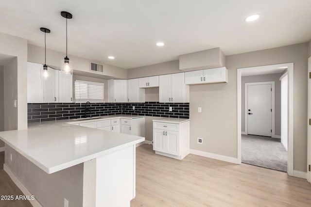 kitchen featuring a peninsula, tasteful backsplash, visible vents, and a sink