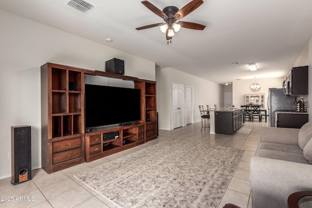 tiled living room featuring ceiling fan with notable chandelier and vaulted ceiling