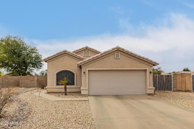 mediterranean / spanish-style house with a tile roof, stucco siding, fence, a garage, and driveway