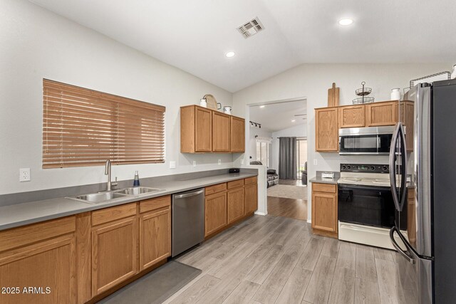 kitchen featuring light wood finished floors, visible vents, appliances with stainless steel finishes, vaulted ceiling, and a sink